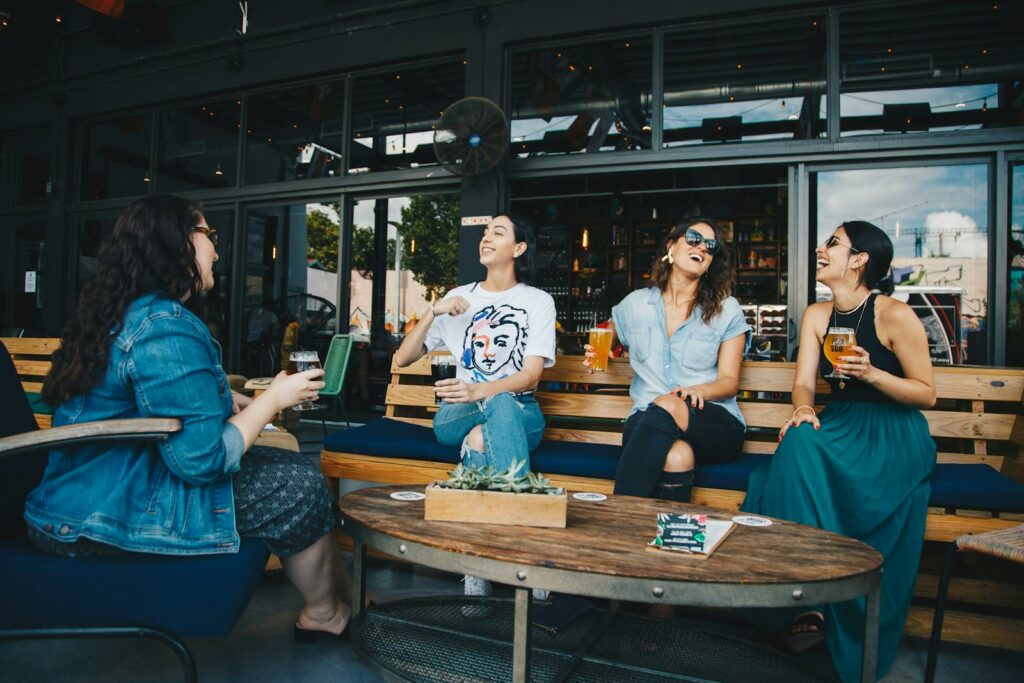 Four Women Chatting While Sitting on Bench