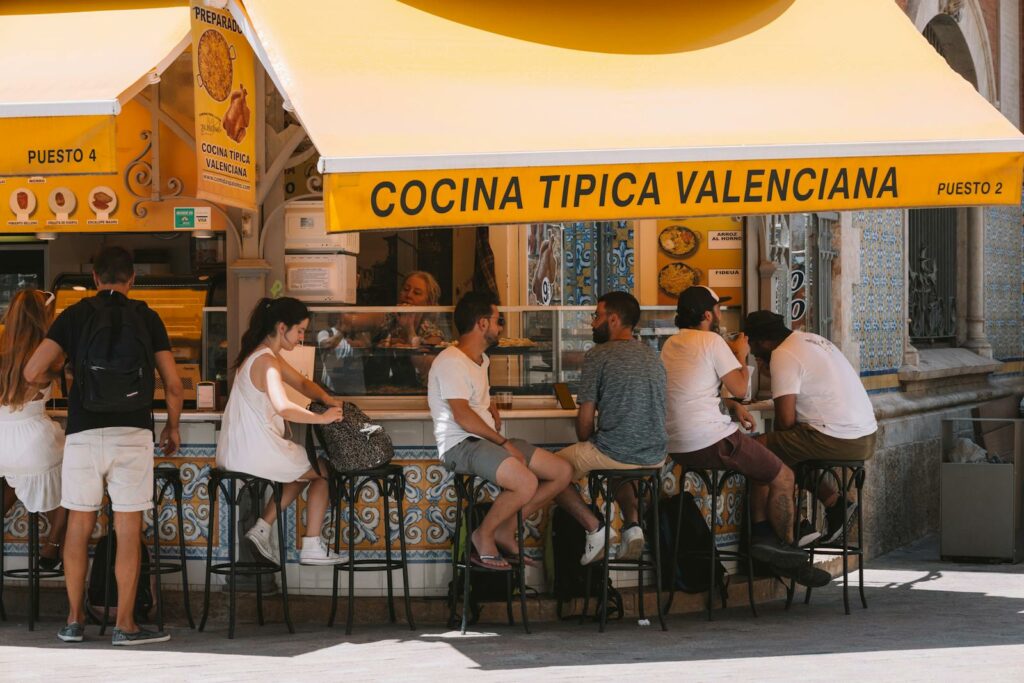 People Sitting at the Counter of a Street Cafe