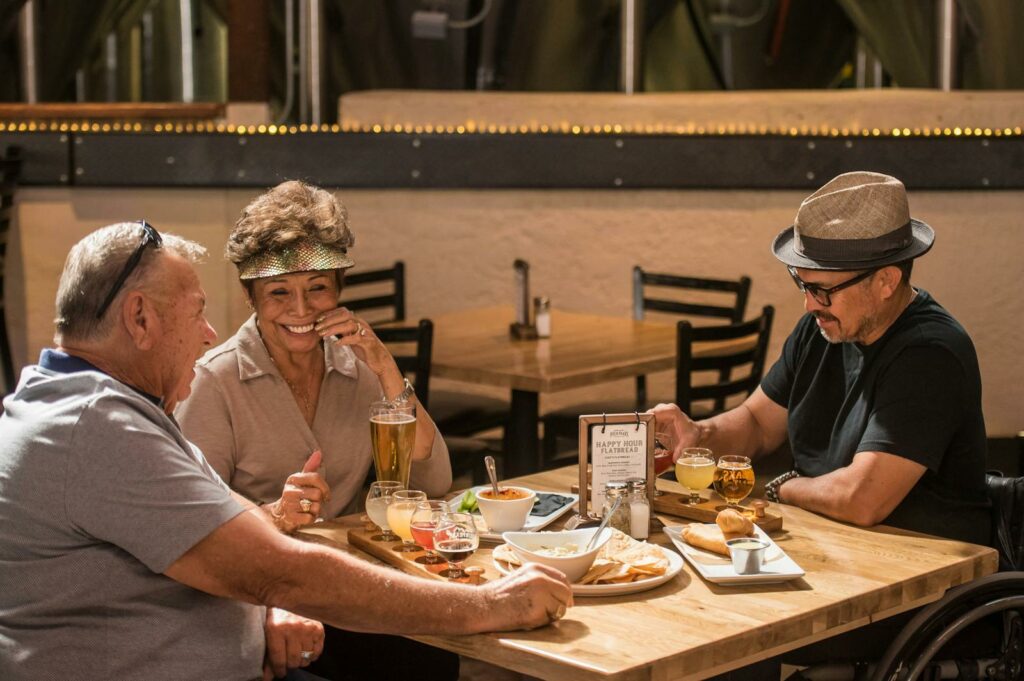 A lively group enjoying craft beer and snacks at an indoor restaurant setting.