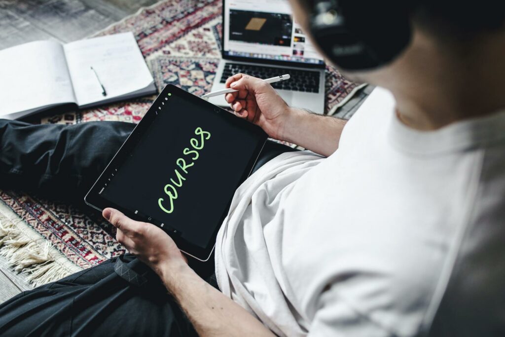 Person studying online courses using a digital tablet while relaxing indoors with headphones.