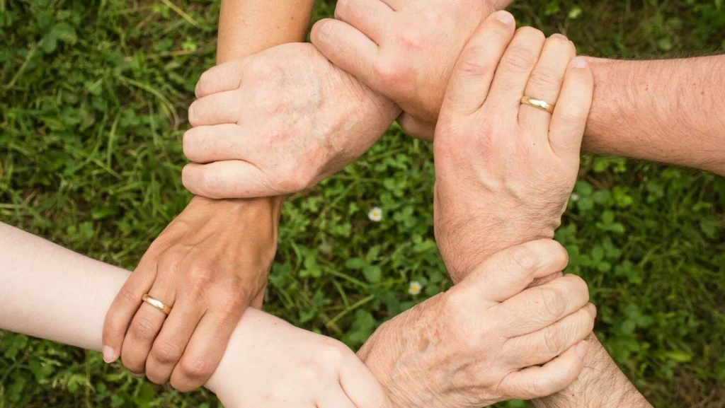 Close-up of diverse hands forming a connection, symbolizing teamwork and unity outdoors.